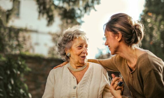 Joyful adult daughter greeting happy surprised senior mother in garden