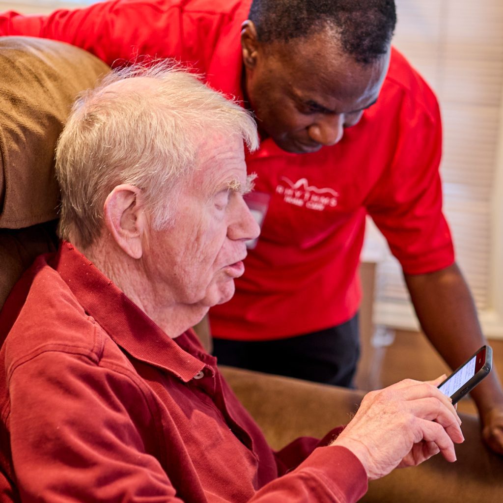 rhythms home care caregiver helping client with smartphone